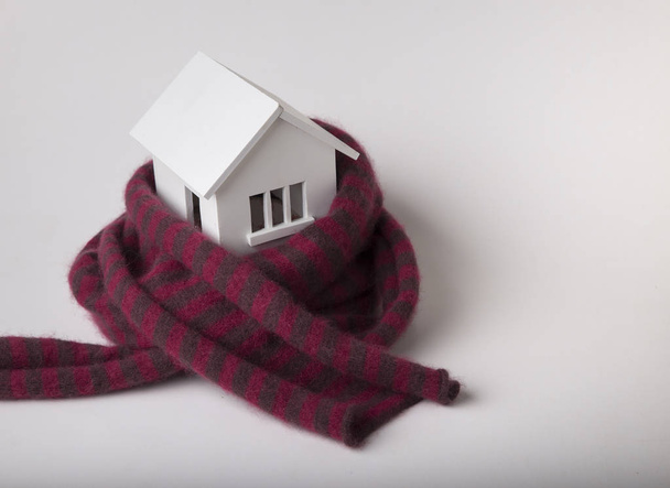 house in winter - heating system concept and cold snowy weather with model of a house wearing a knitted cap - Foto, imagen