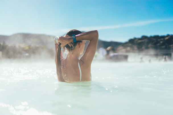 rear view of young woman relaxing in hot pool in Iceland  - Photo, Image