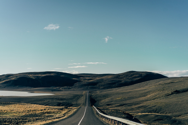 tyhjä asfalttitie luonnonkauniiden kukkuloiden välissä Islannissa
 - Valokuva, kuva
