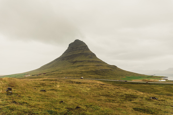 schöne grüne Hügel mit Pflanzen und Straße in Island bedeckt  - Foto, Bild