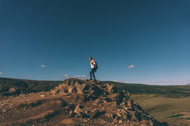 jonge vrouw staande op de klif en prachtige landschap in IJsland  - Foto, afbeelding