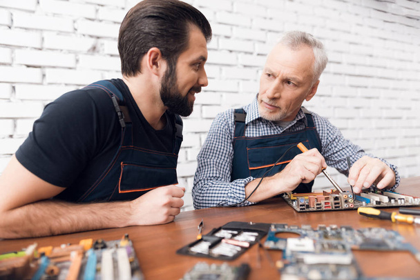 Adult and young men repair parts from the computer together. - Foto, immagini