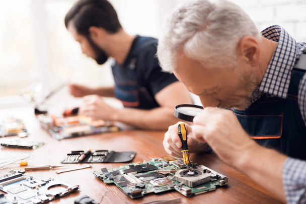 Adult and young men repair parts from the computer together. - Foto, Imagem