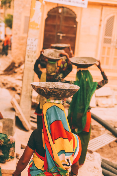 πίσω όψη των γυναικών σε φωτεινά παραδοσιακά ρούχα που μεταφέρουν κύπελλα για κεφαλές, rajastan, jeisalmir - Φωτογραφία, εικόνα