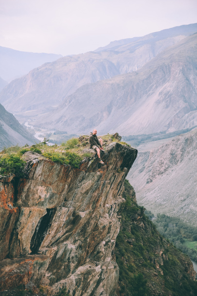 homem sentado no penhasco e olhando para majestosas montanhas em Altai, Rússia
   - Foto, Imagem