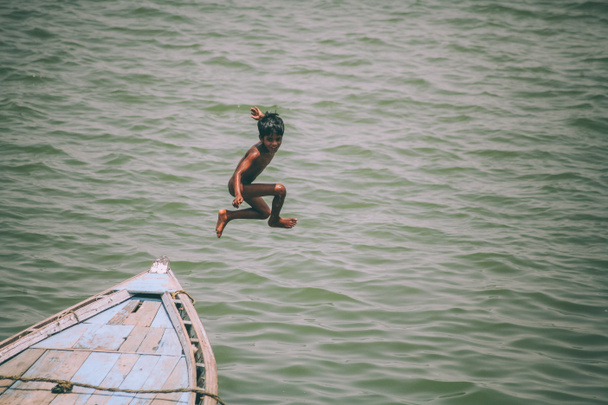 adorable little boy jumping from boat in Varanasi, India - Fotoğraf, Görsel