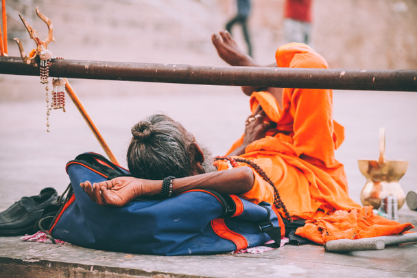 monge em roupas laranja brilhante descansando em Varanasi, Índia
 - Foto, Imagem