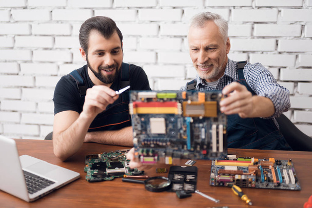 Adult and young men repair parts from the computer together. - Foto, Bild