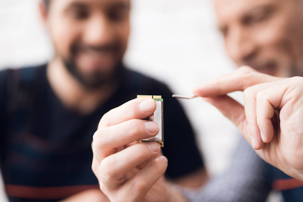 Adult and young men repair parts from the computer together. - Photo, Image