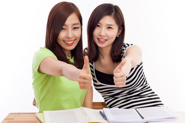 Nuori aasialainen opiskelija naiset osoittavat peukalo pöydällä
 - Valokuva, kuva