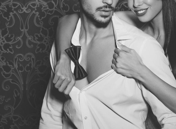 sexy Frau entkleidet trendige Macho-Mann drinnen schwarz und weiß - Foto, Bild