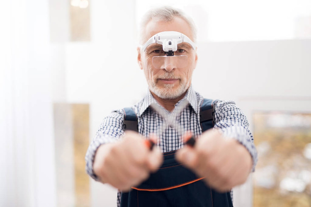 An elderly man is posing on the camera with a screwdriver. - Fotoğraf, Görsel