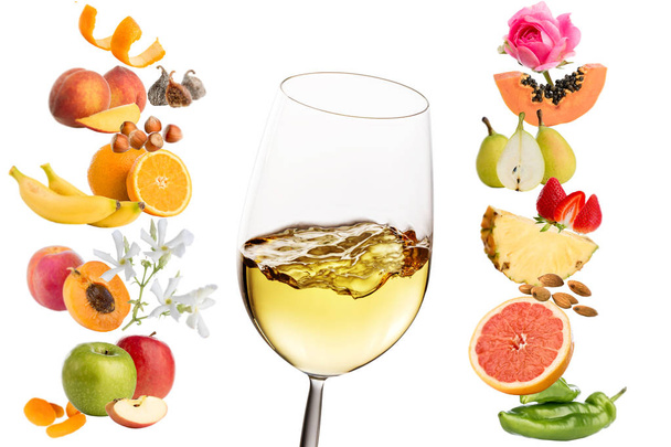 Koncepcyjne aromaty owoców i kwiatów wokół szkła z białego wina. Na białym tle. - Zdjęcie, obraz