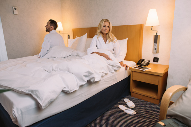 Starsza para w szlafroki, siedząc na łóżku w pokoju hotelowym - Zdjęcie, obraz
