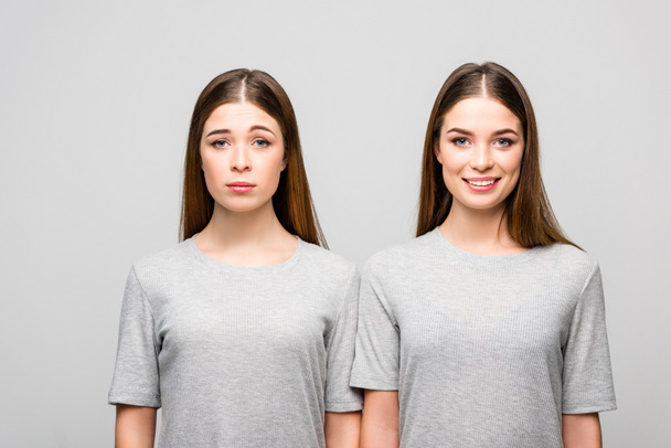 gri tişörtleri gri izole duygular gösterilen ikiz kız portresi - Fotoğraf, Görsel