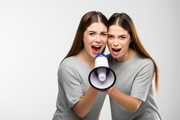 portrait of young twins screaming into loudspeaker in hands - Φωτογραφία, εικόνα