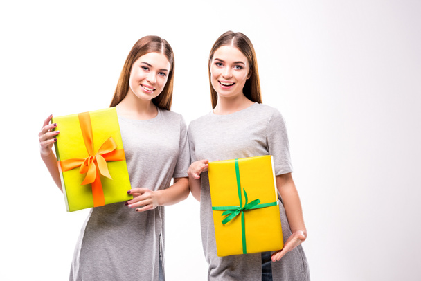 portrait of cheerful twins holding wrapped gifts in hands - Foto, Imagem