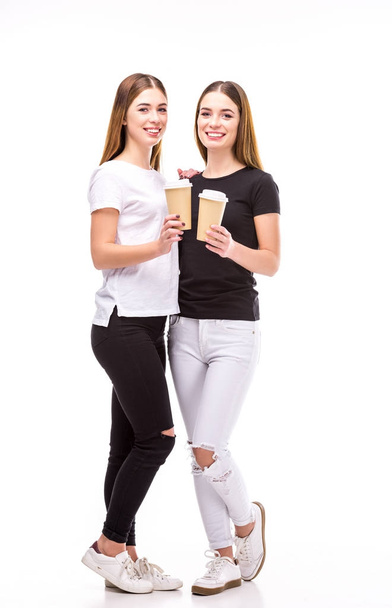 gemelos alegres con café para ir en las manos mirando a la cámara aislada en blanco
 - Foto, imagen