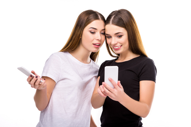 portrait of beautiful twins with smartphones isolated on white - Foto, imagen