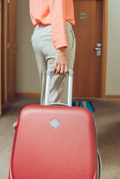 cropped shot of woman with suitcase walking through hotel hallway - Фото, изображение