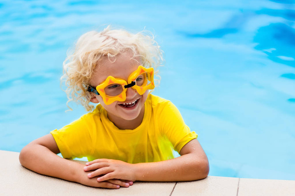 Child with goggles in swimming pool. Kids swim. - Photo, Image