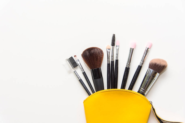 Makeup cosmetics tools background and beauty cosmetics, products and facial cosmetics package lipstick, eyeshadow in yellow bag on the white background.  Lifestyle Concept. - Zdjęcie, obraz