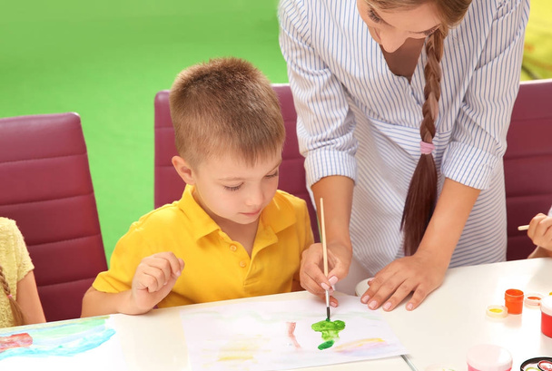 Kleiner Junge mit Lehrer bei Malstunde im Klassenzimmer - Foto, Bild