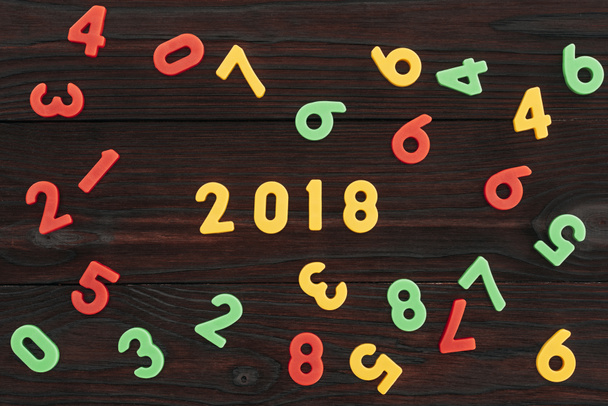 vista superior de coloridos números de 2018 en la superficie de madera oscura
 - Foto, imagen