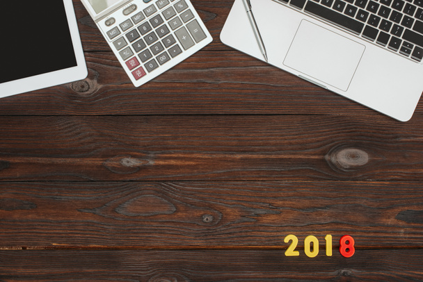 верхний вид ноутбука, планшета, калькулятора и номера 2018 года на деревянном столе
 - Фото, изображение