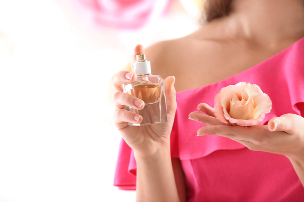Beautiful young woman with bottle of floral perfume on light background, closeup - Foto, afbeelding