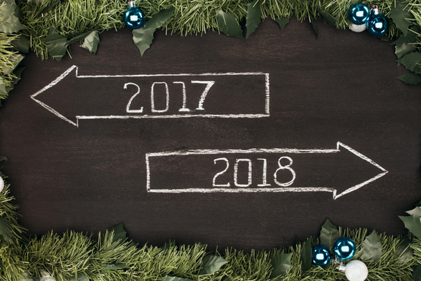 bovenaanzicht van 2017, 2018 jaar borden met kerstversiering rond op donkere houten oppervlak - Foto, afbeelding