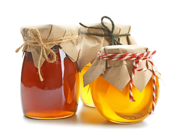 Jars with aromatic honey on white background - Фото, зображення