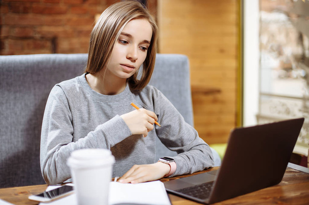 Jonge mooie vrouw is het gebruik van laptop in een café - Foto, afbeelding