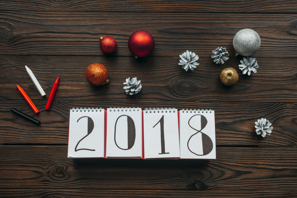 flat lay with 2018 calendar, pencils and christmas toys on wooden surface - Fotó, kép