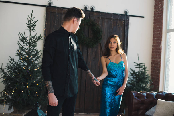  Beautiful elegant couple of lovely man and girl hold handsome look away. Christmas atmosphere in the home location. Scandinavian interior with a Christmas Tree.  - Photo, Image