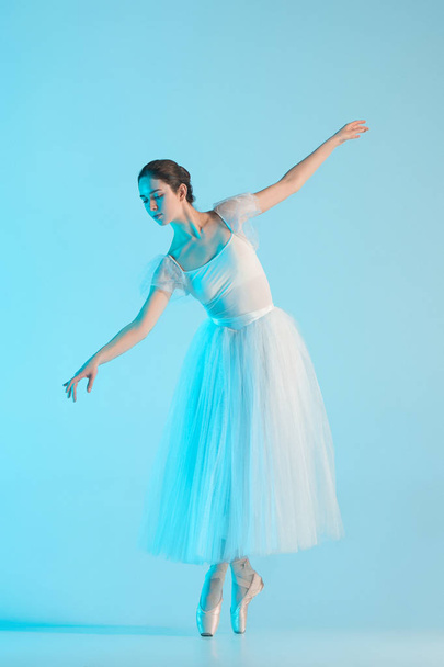 Young and incredibly beautiful ballerina is dancing in a blue studio - Photo, Image