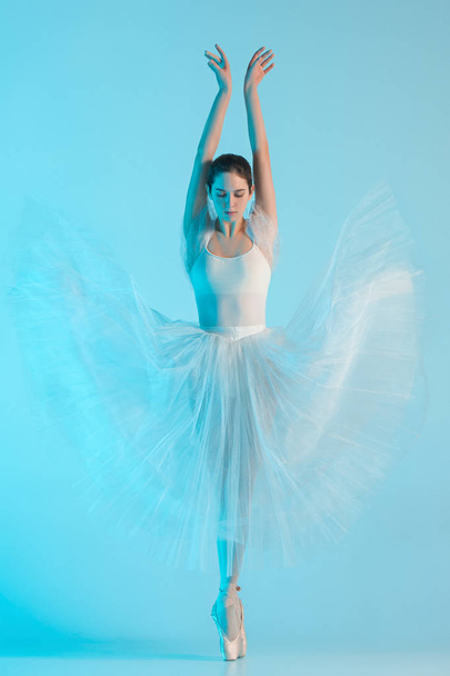 Young and incredibly beautiful ballerina is dancing in a blue studio - Фото, зображення