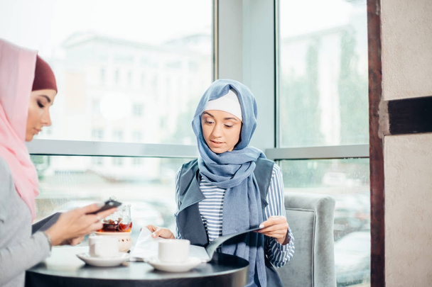 mujer musulmana de negocios documentos de trabajo en la cafetería
 - Foto, Imagen