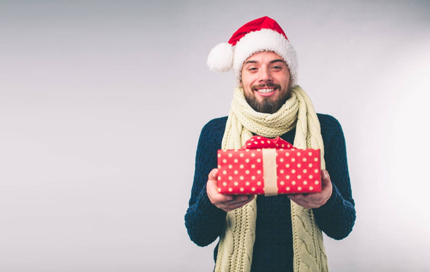 Handsome man in a Christmas hat holding gifts on white background - Фото, изображение