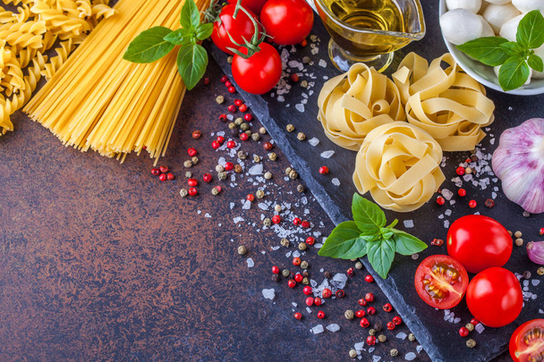 Ингредиенты для макарон с моцареллой и помидорами на тёмном фоне, горизонтально, копипространство
 - Фото, изображение