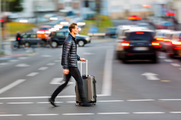 businessman with trolley bag crosses the street - Foto, Bild