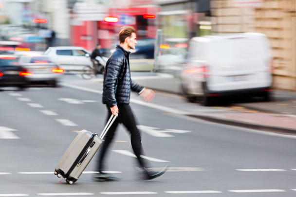 zakenman met trolley tas kruist de straat - Foto, afbeelding