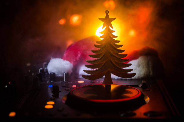 DJ keverő fejhallgató, a sötét éjszakai háttér karácsonyfa Szilveszter. Közelről újév elemek vagy szimbólumokat (Mikulás, hóember, kutya 2018, díszdobozban) Dj tábla. tónusú - Fotó, kép