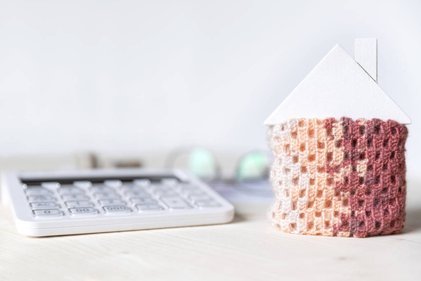 House wrapped in a scarf next to the calculator. money saving on - Фото, изображение
