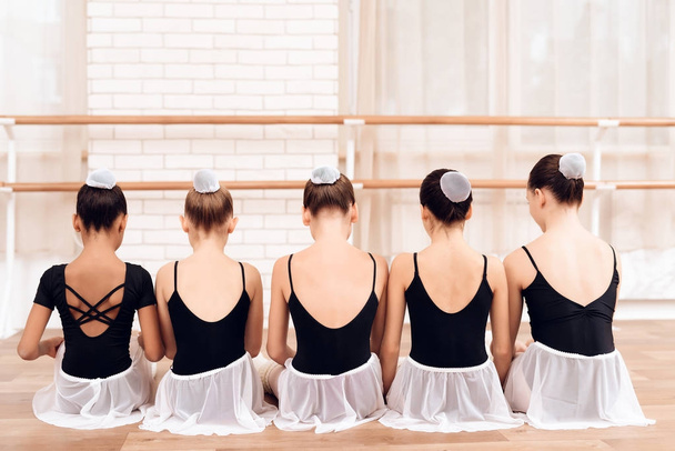 Young ballerinas perform various choreographic exercises sitting on the floor. - Foto, Bild