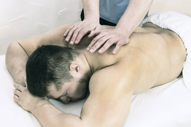 The process of health-improving sports massage is done by a man in a medical clinic - Fotó, kép