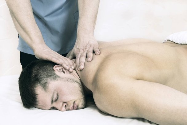 The process of health-improving sports massage is done by a man in a medical clinic - Фото, зображення