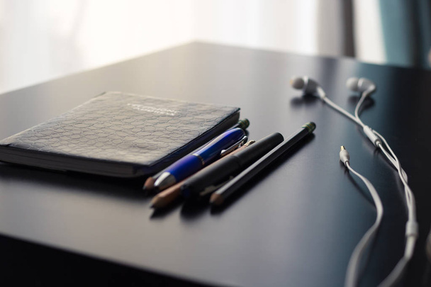 Office supplies are set on a shiny and reflective office desk. The objects on the desk signify the concept of old versus new technology. The interactive natural light and shadows create a simple yet compelling and contrasting image.  - Photo, Image
