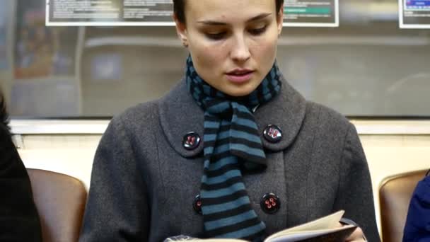 A girl is reading a book in a subway car - Séquence, vidéo