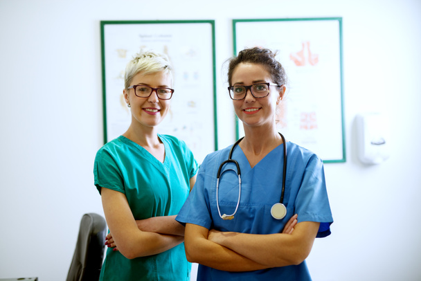 portrait of two professional happy nurses with eyeglasses standing in hospital - Fotó, kép